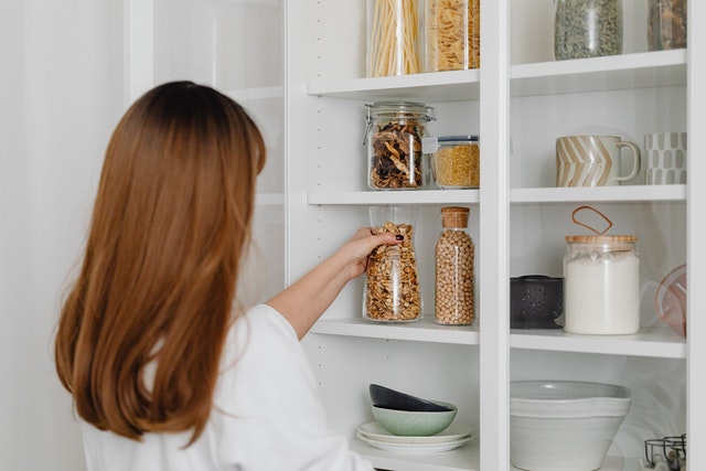 A woman reaching for cooking items on her pantry shelves 