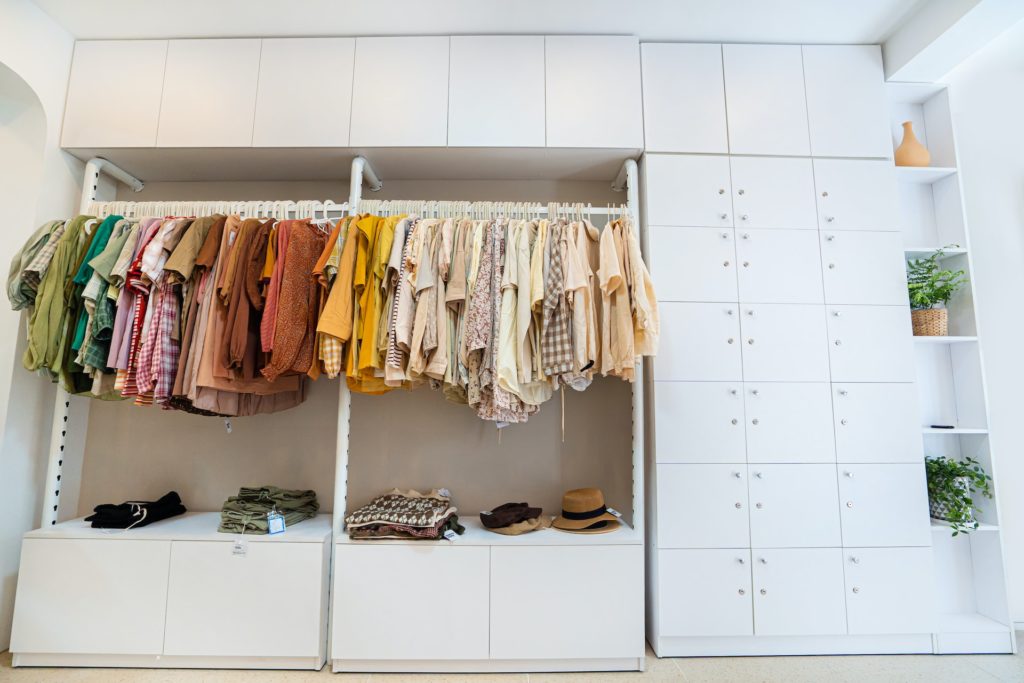 A closet built into a wall with a rod for hanging clothes and cupboards for storage. 