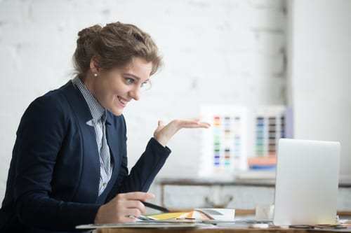 A business women sitting at a computer talking with a client. 