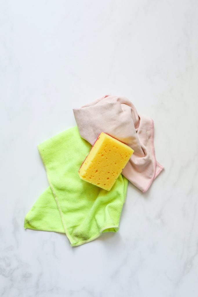 a green cloth a yellow sponge and another beige drying cloth