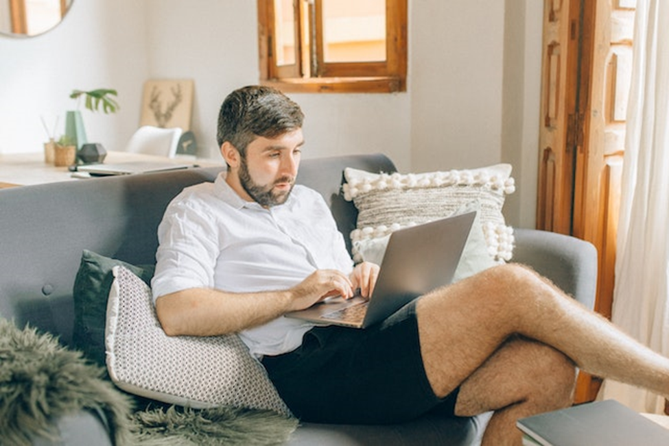 Man sitting on the couch and using a laptop.